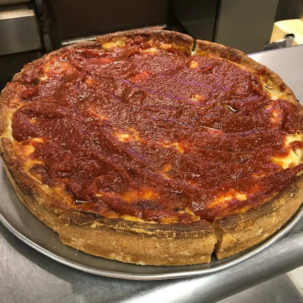A deep-dish pizza with a thick crust, covered in rich red tomato sauce and melted cheese.