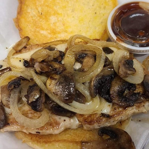 Grilled chicken sandwich with melted cheese, sautéed onions, mushrooms, and a side of BBQ sauce.